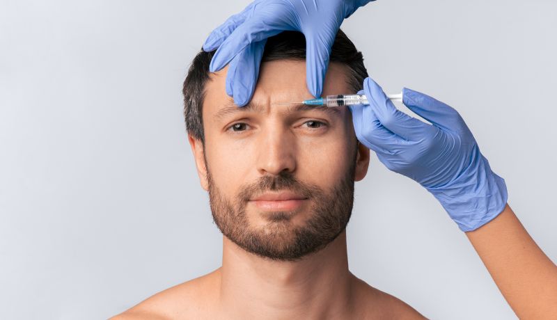Injeções de bioestimulador de colágeno sendo aplicadas na testa de um homem para redução de rugas e rejuvenescimento facial.
